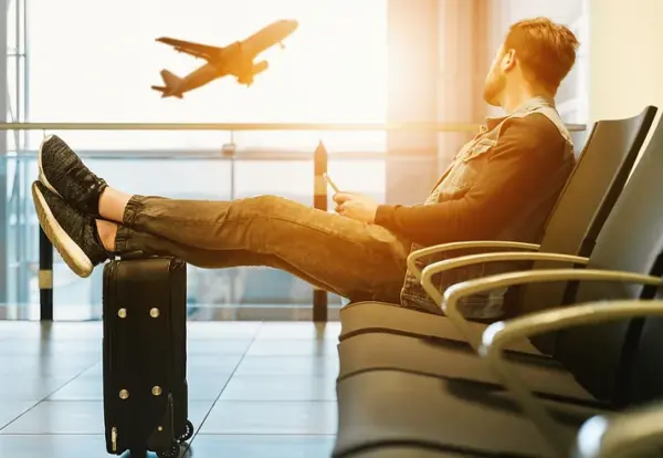 man sitting at airport watching plane take off