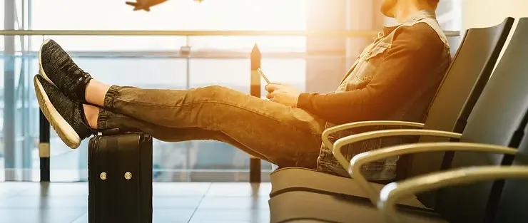 man sitting at airport watching plane take off