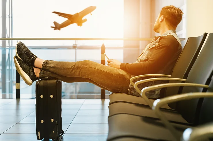 man sitting at airport watching plane take off