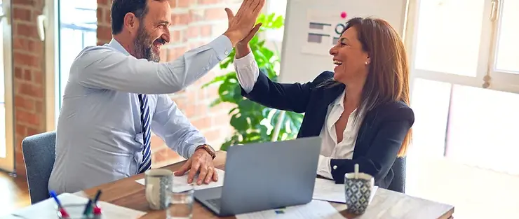 Two coworkers high fiving in office