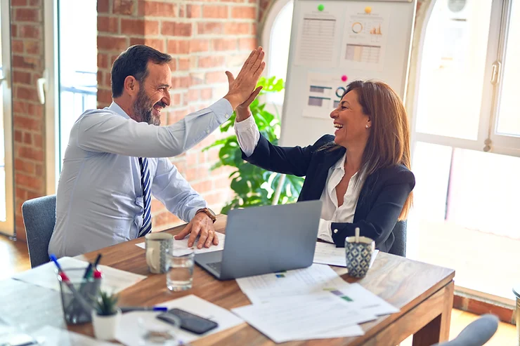 Two coworkers high fiving in office