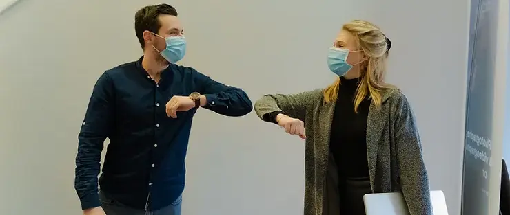 two people elbow bumping wearing masks