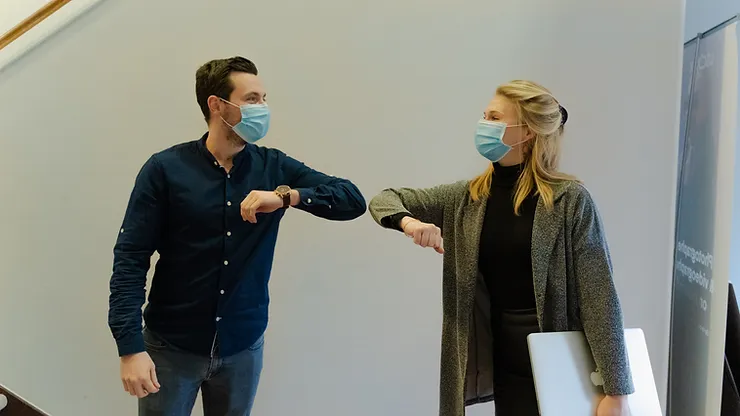 two people elbow bumping wearing masks